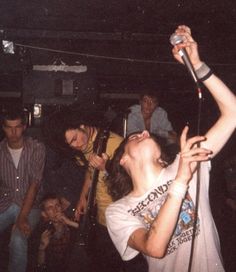 a man singing into a microphone while standing next to other people