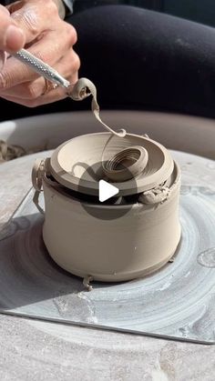 a person working on a pottery wheel with a small piece of metal in his hand