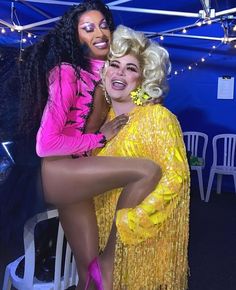 two women dressed in yellow and pink posing for the camera with one woman leaning on her back