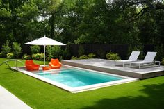 an outdoor pool with lounge chairs and umbrellas in the grass next to some trees