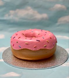 a pink frosted doughnut with sprinkles on a silver platter