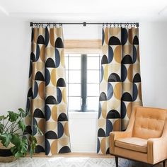 a living room with a chair, window curtain and potted plant on the floor