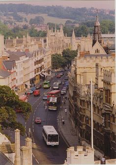 a city street filled with lots of traffic next to tall buildings on either side of the road