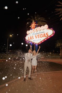 two people standing in front of the las vegas sign with snow falling all around them