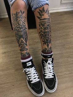 the legs and ankles of a person with tattoos on them, both wearing black sneakers