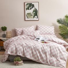 a pink and white checkered comforter set on a bed in a room with potted plants