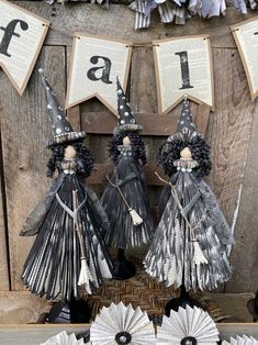 three paper witches are standing in front of an old book page sign that says fall