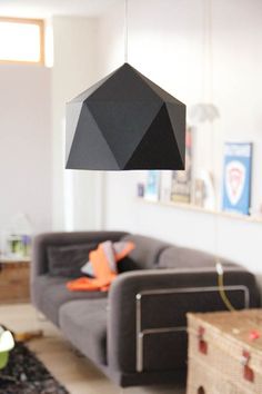 a living room filled with furniture and a black lamp hanging over it's head