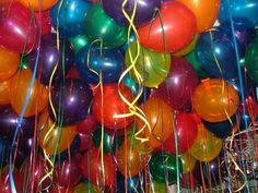 a bunch of balloons that are in the air with some streamers on top of them