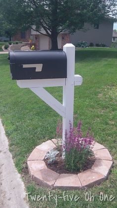 a mailbox is in the middle of a flower bed with purple flowers growing out of it