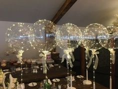 some clear balloons with lights on them are in the middle of a dining room table