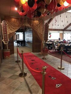 a red carpet with gold poles and balloons hanging from it's ceiling in a restaurant