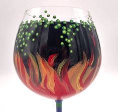 a wine glass painted with fire and green beads