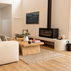 a living room filled with furniture and a fire place in the middle of it on top of a hard wood floor