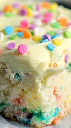 a piece of cake with white frosting and colorful sprinkles on it