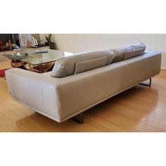 a white couch sitting on top of a hard wood floor next to a glass table