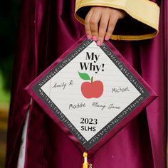 a woman in a graduation gown holding up a sign that says, my why?