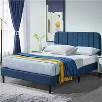 a blue bed with white sheets and pillows in a room next to a mirror on the wall