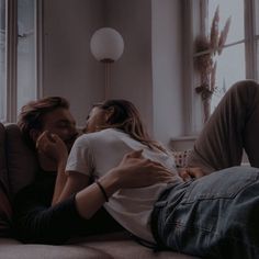 a man and woman are laying on the couch looking into each other's eyes