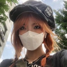 a woman with red hair wearing a white face mask and black beret on her head