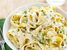 a white bowl filled with pasta covered in parmesan cheese and garnished with chives