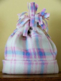 a pink and blue checkered hat with a bow on the top sitting on a wooden table