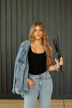 a woman is holding two hair dryers in one hand and a pair of scissors in the other