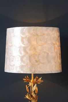 a lamp that is on top of a table with a white shade over the lamp