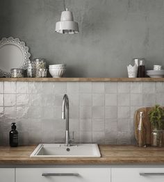 a white kitchen sink sitting under a mirror next to a counter top with dishes on it