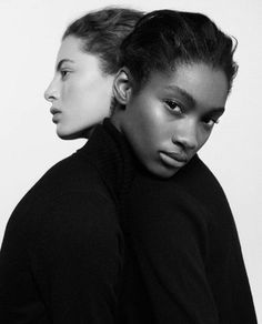 two women in black sweaters standing next to each other with their heads tilted back