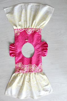 a pink and white dog dress with ruffles on the collar, sitting on top of a wooden table