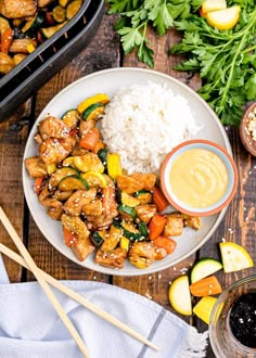 a white plate topped with chicken and veggies next to rice