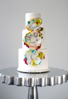 a three tiered white cake with colorful flowers on it