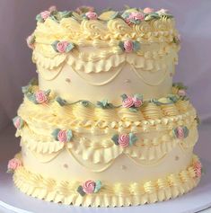 a three tiered cake decorated with flowers and icing on a white platter