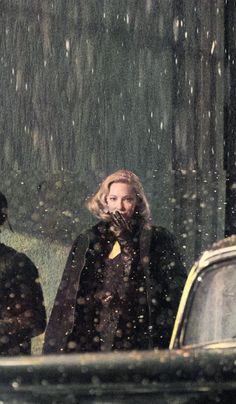 black and white photograph of two women walking in the snow with an umbrella over their heads