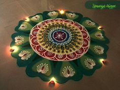 a green and red flower design on the ground with lights around it for diwaling