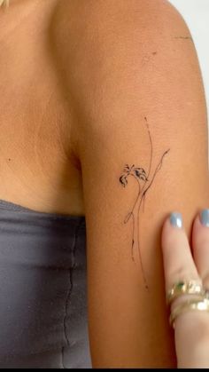 a woman's arm with a small tattoo on the back of her left shoulder