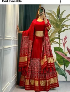 a woman in a red and gold lehenga taking a selfie