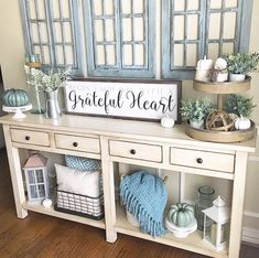 a white table topped with lots of furniture and decor next to a blue shuttered window