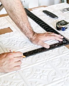 a man measuring the width of a mattress with a ruler and tape on top of it