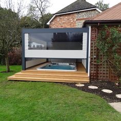 an outdoor hot tub in the middle of a yard with a wooden deck and green grass