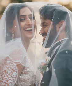 the bride and groom are smiling under their veil