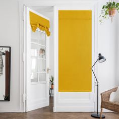 an open door with yellow blinds in a white room