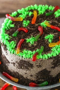 there is a cake with green frosting and gummy worms on the top of it