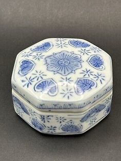 a small blue and white box sitting on top of a gray surface with an intricate design