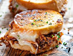 two grilled cheese sandwiches sitting on top of a wooden cutting board