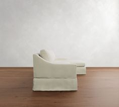 a white couch sitting on top of a hard wood floor next to a chair and ottoman