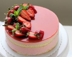 a strawberry cheesecake on a white plate topped with fresh strawberries and mint leaves