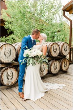 a bride and groom kissing in front of wine barrels