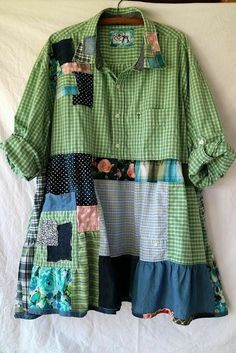 a green shirt with patchwork on it hanging from a hanger in front of a white sheet